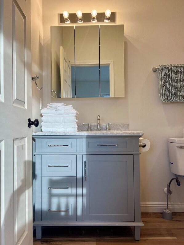 A bathroom with a vanity, sink, mirror, and toilet.
