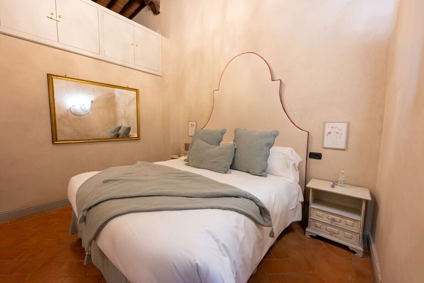 A bedroom with a bed, a nightstand, a bedside table, a framed picture, and a wardrobe.