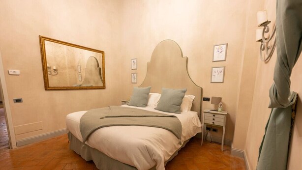 A bedroom with a bed, bedside tables, a nightstand, a wall-mounted lamp, and a framed picture. - Avignonesi - Tuscan Palace (Montepulciano)