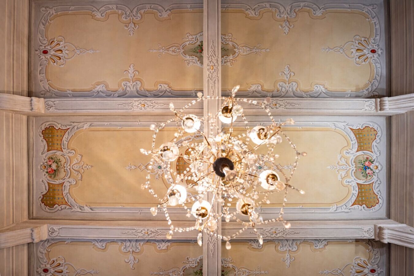 An ornate ceiling with a chandelier and decorative moldings.