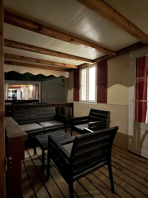 Une pièce avec un banc en bois, une table et une fenêtre avec des volets.