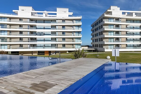 A modern hotel with a rooftop pool, multiple balconies, and a clear view of the surrounding area. - Oceana Suites Lumiere (Punta del Este)
