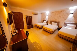 Habitación de hotel con dos camas, un escritorio, una silla, un armario y un equipo de aire acondicionado.