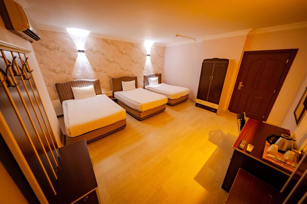 Una habitación de hotel con dos camas individuales, un armario, un escritorio con hervidor y un radiador.