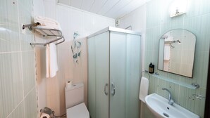 A bathroom with a toilet, sink, and glass-enclosed shower. - Koçaklar Otel (Karapınar)