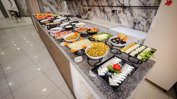 Un bufé con diferentes opciones de comida y una pared de mármol al fondo.
