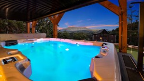 A hot tub with a view of mountains at dusk. - New! Loaded Luxe w/Pool*Theater*Game Room*Views! (Sevierville)