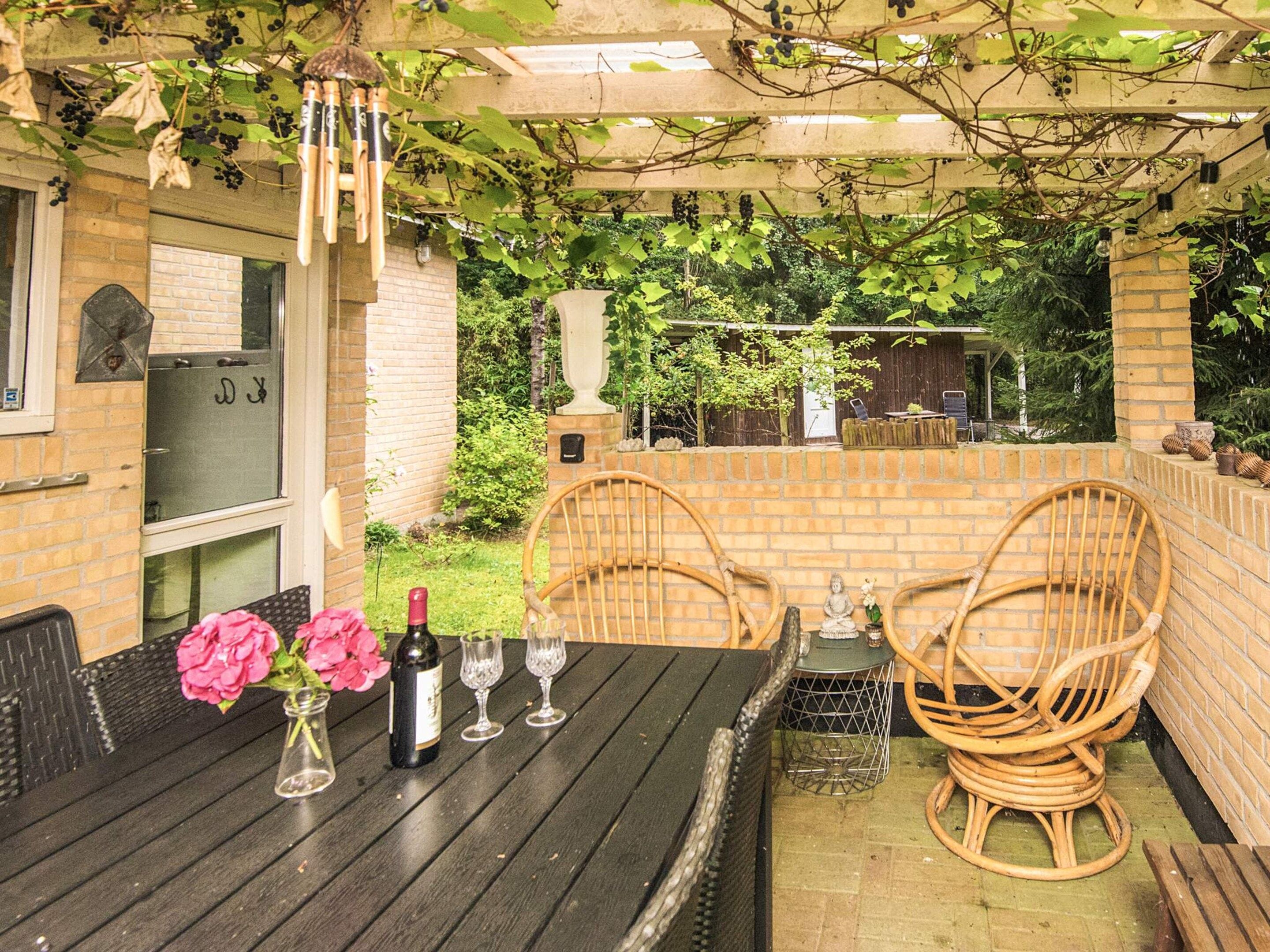 An outdoor patio with a table set for dining, surrounded by brick walls and greenery.