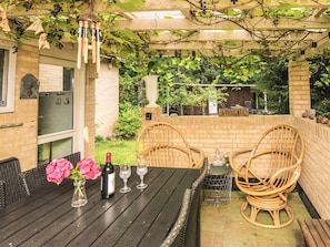 An outdoor patio with a table set for dining, surrounded by brick walls and greenery. - 4 Person Holiday Home in Ans By (Ans)