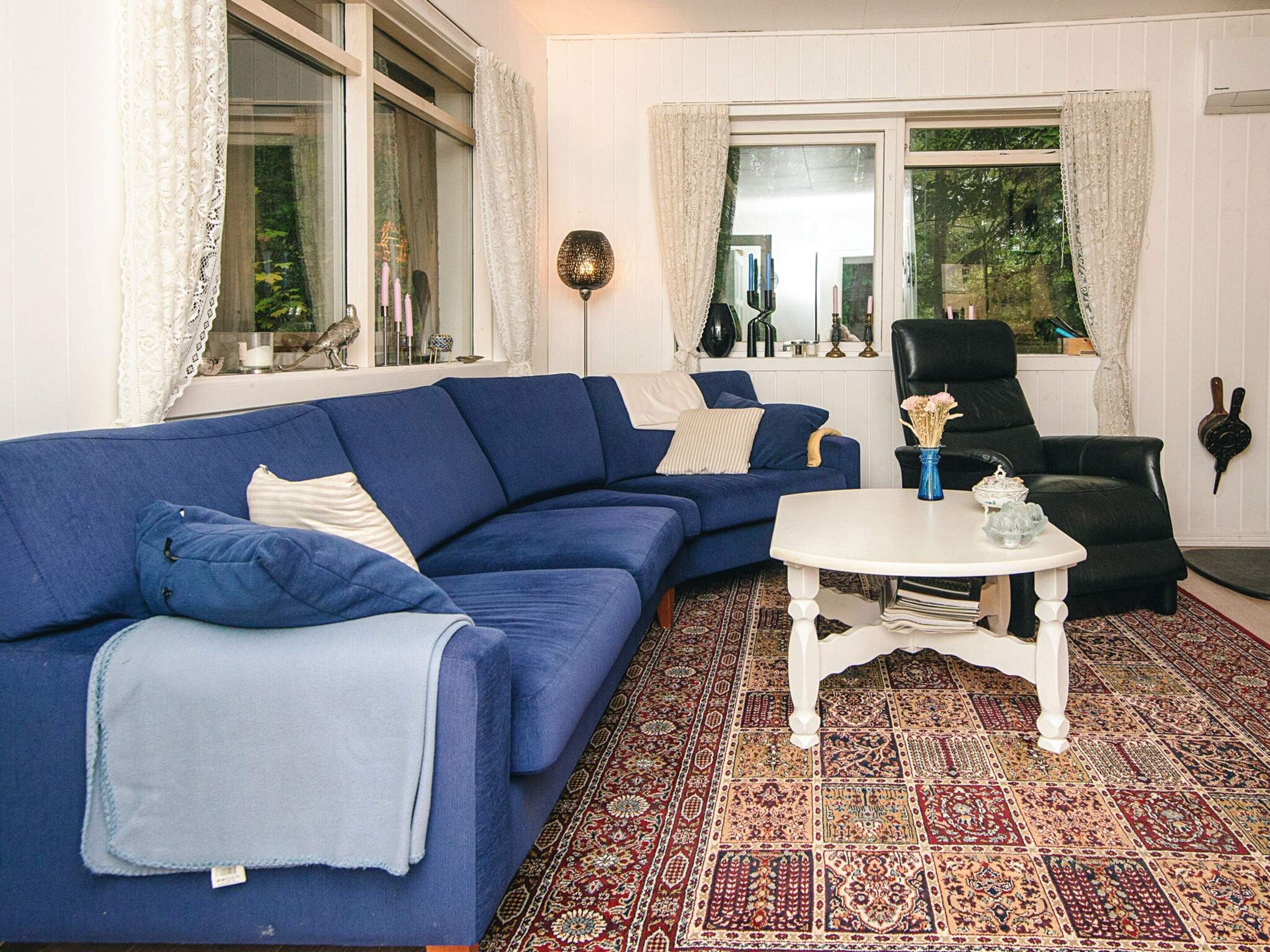 A living room with a blue sofa, a white coffee table, and a patterned rug.