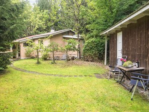 A residential property with a brick house, a wooden fence, a grassy yard, and a table with outdoor seating.