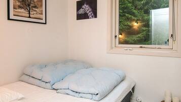 A bedroom with a bed, a window with a view of trees, and two framed pictures on the wall.