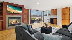 Un salon moderne avec une cheminée, un grand téléviseur et une vue sur la plage.