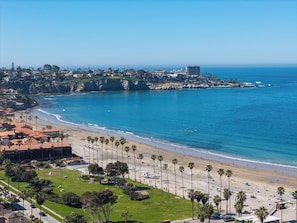 Eine Küstenstadtlandschaft mit Strand, Palmen und Gebäuden.