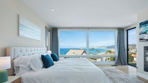Une chambre avec un grand lit, une vue sur l’océan et un panorama sur la ville.