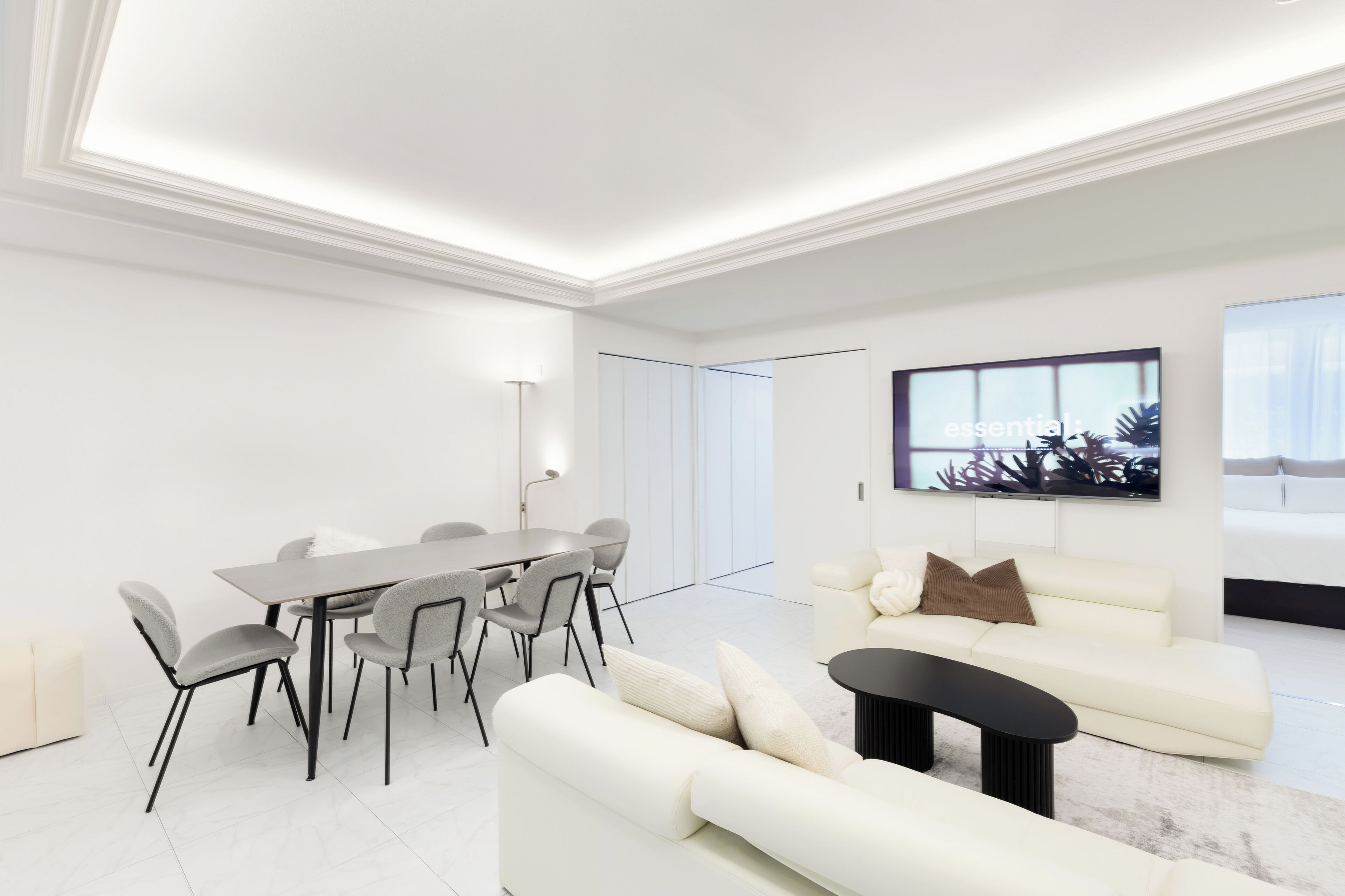 Una sala de estar moderna con comedor, paredes blancas y un ventanal grande.