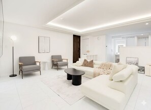 A modern living room with a white sofa, two armchairs, a coffee table, and a floor lamp.