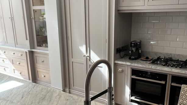 A modern kitchen with white cabinetry, a marble countertop, a stainless steel sink, and a gas stove.