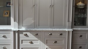 A spacious room with a large white cabinet with multiple drawers and doors, a skylight above, and a wooden floor.
