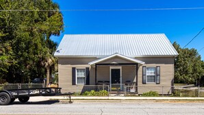 A single-story house with a metal roof, a front porch, and a small attached garage.