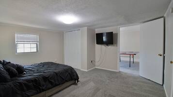 A bedroom with a bed, a television mounted on the wall, and a door leading to another room.