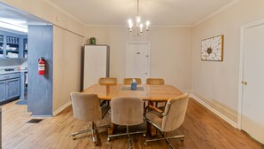 A conference room with a wooden table, six chairs, a chandelier, a fire extinguisher, and a door.