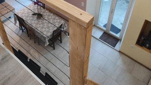 A dining area with a table and chairs, a wooden railing, an air conditioning unit, and a sliding glass door leading outside. - House near the train station with outdoor space (Neufchâteau)
