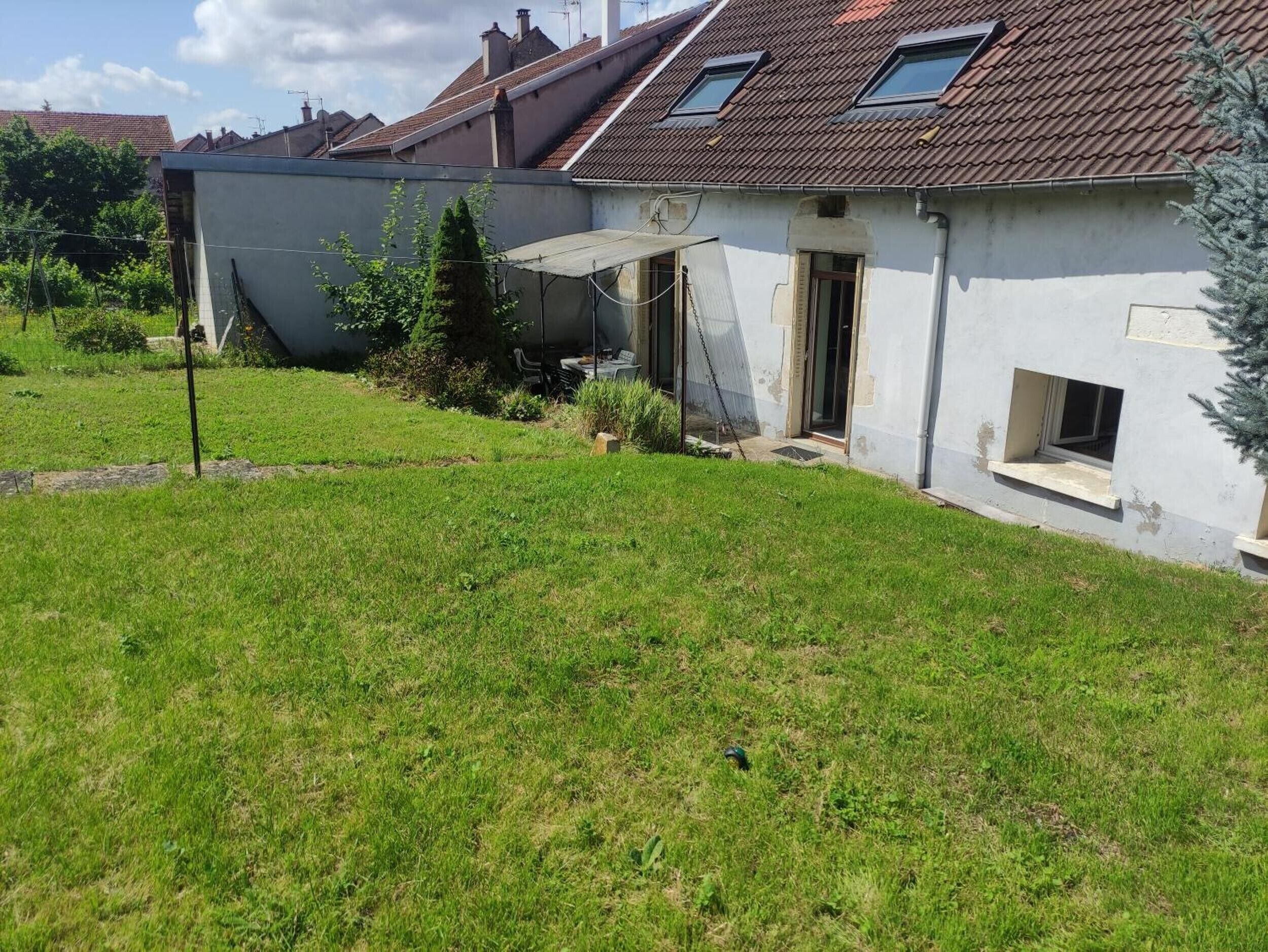 A residential property with a sloped roof, a small garden, and a detached garage.