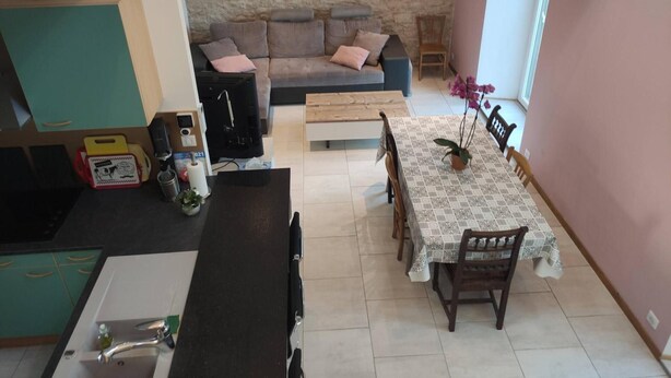 A compact living space with a kitchenette, a sofa set, a dining table, and a small window with an orchid plant. - House near the train station with outdoor space (Neufchâteau)