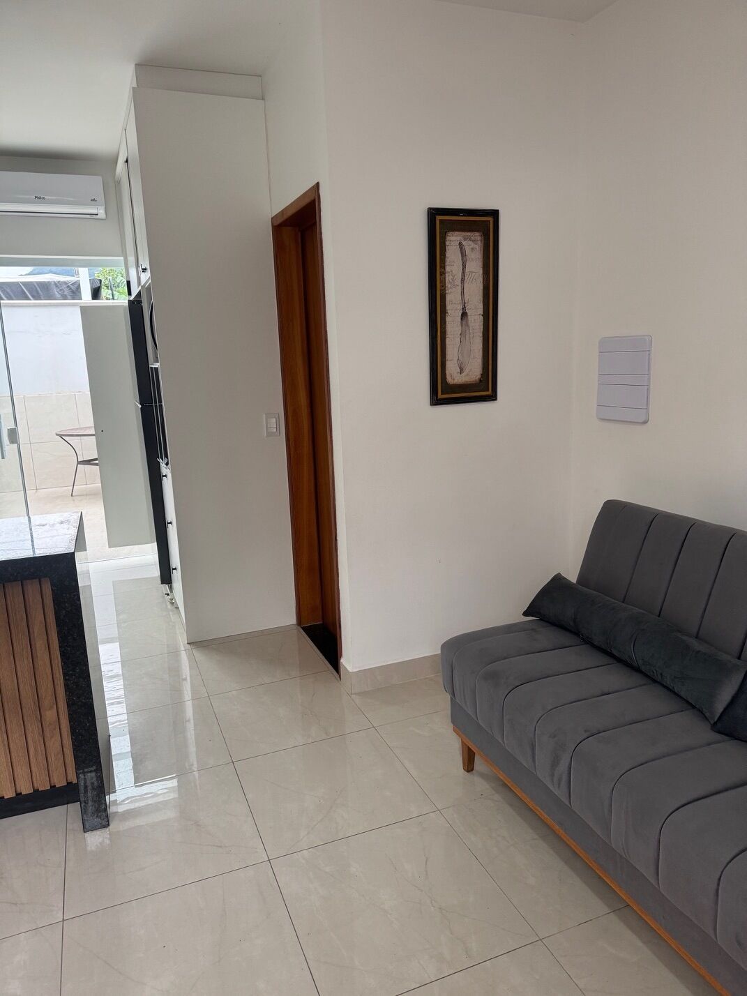 Un salon moderne avec un canapé gris, une table d’appoint en bois et un tableau encadré accroché au mur.