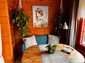 Et hyggeligt rum med trævægge, et rundt træbord, en blå sofa og hængende planter.