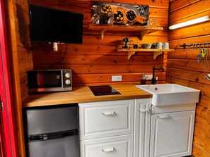 A compact kitchen with a microwave, toaster, sink, and a small refrigerator.