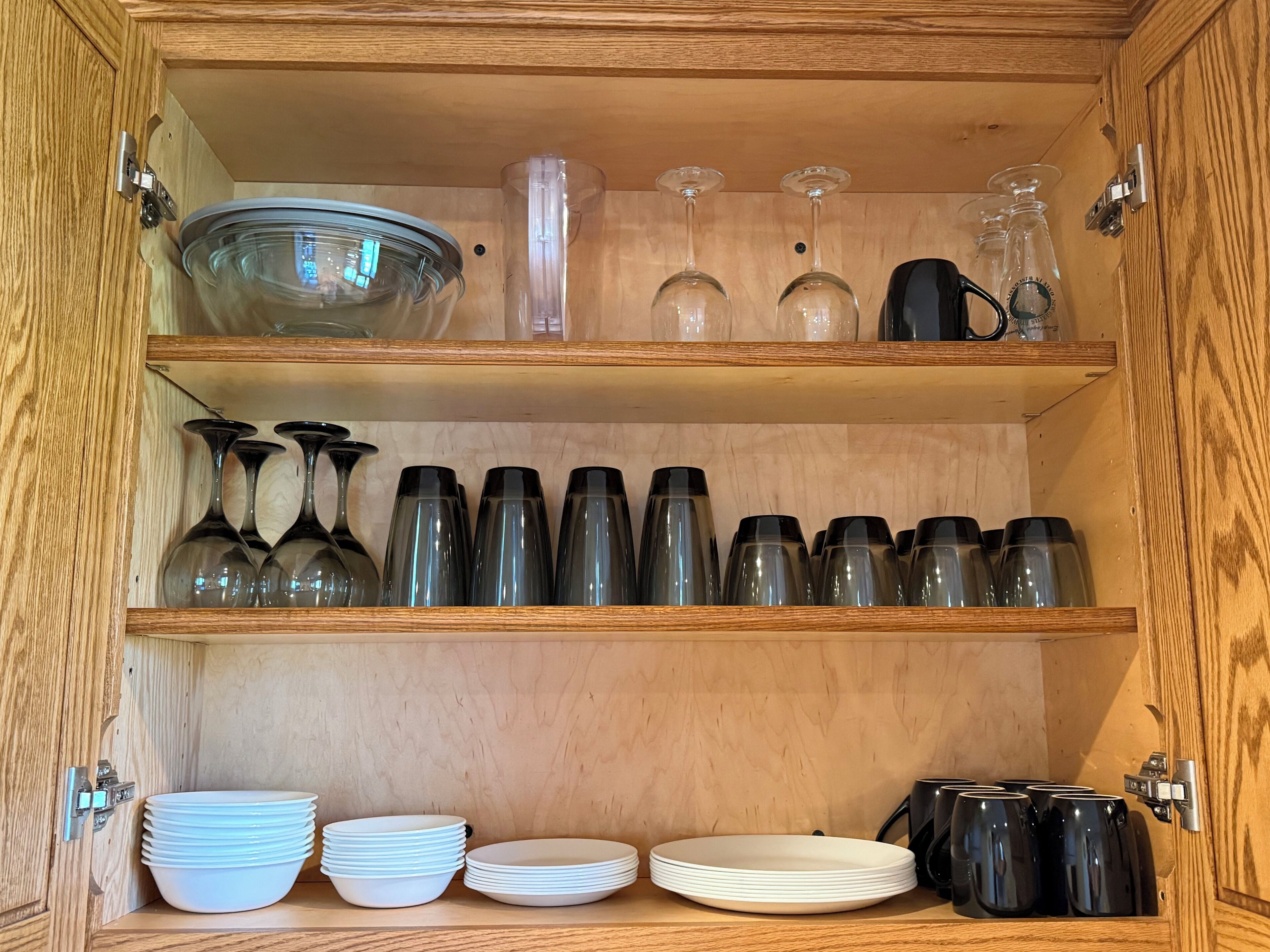 Un meuble en bois doté d’étagères où sont rangés de la verrerie, des assiettes et une machine à café.