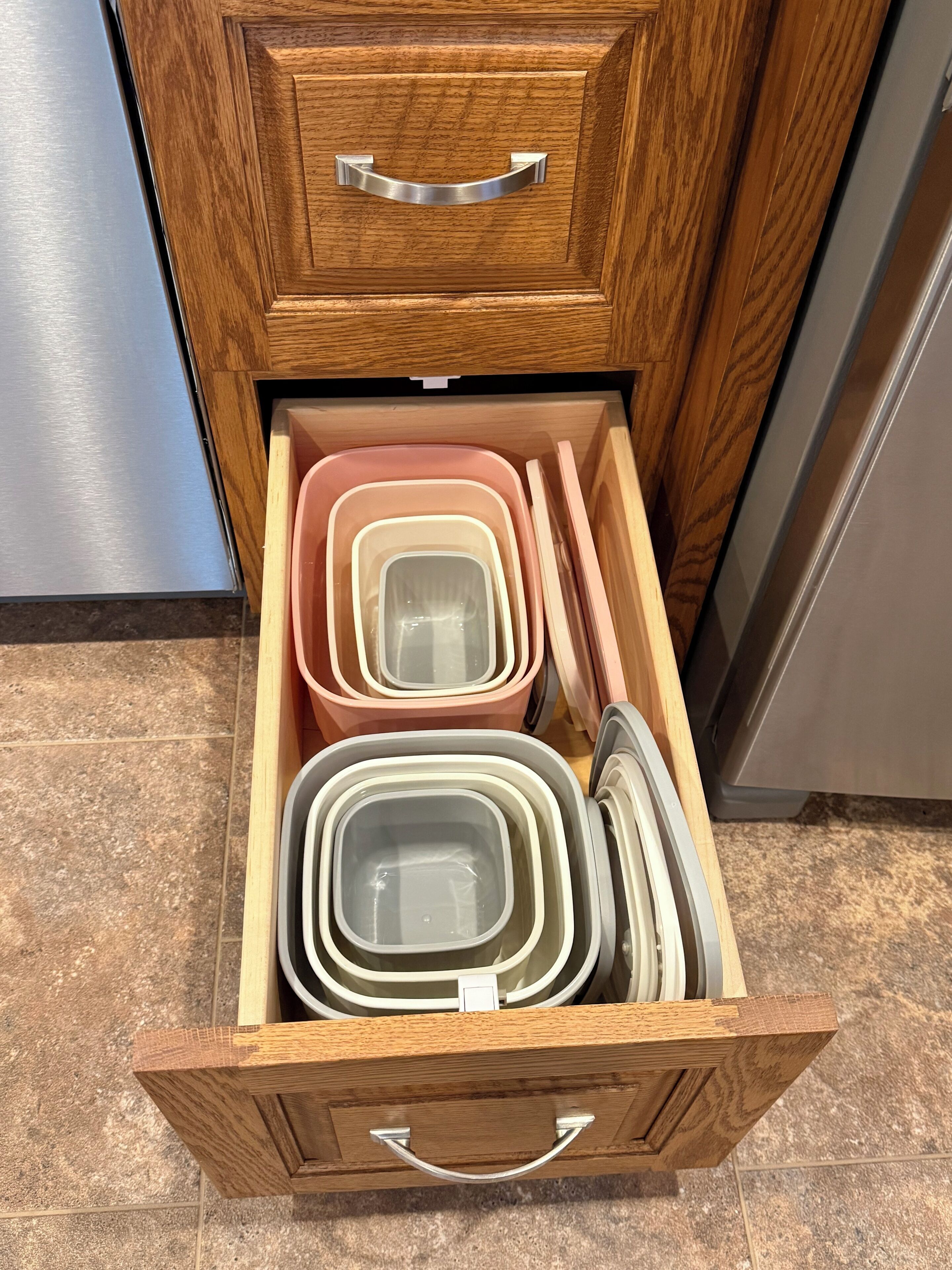 A wooden drawer with multiple plastic containers.