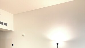 Ein modernes Wohnzimmer mit einem grauen Ecksofa, einem Glastisch und einer Stehlampe.