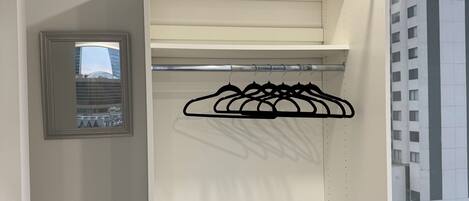 A walk-in closet with open shelves and a black hanger rack.