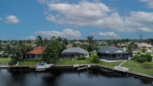 A residential area with houses, a dock, and a body of water. - Southern Exposure - 4bed/3bath - Sands Area - Stars Vacation Rentals (Cape Coral)