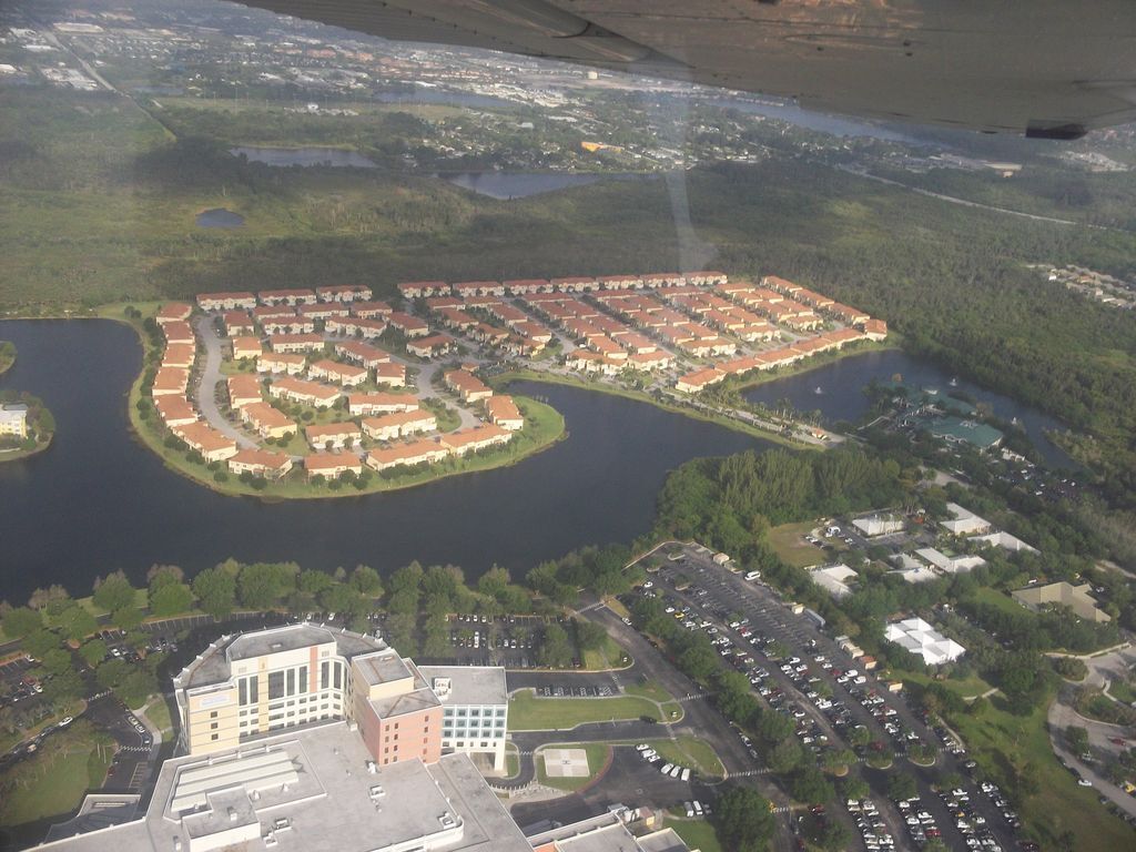 An aerial view of a residential area with a circular lake surrounded by houses.