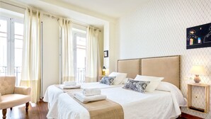 Habitación de hotel con dos camas, una silla, una mesita de noche y una lámpara fijada a la pared.
