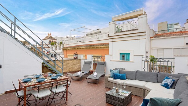 Una terraza en la azotea con mesa de comedor, sillas de descanso y sofá.