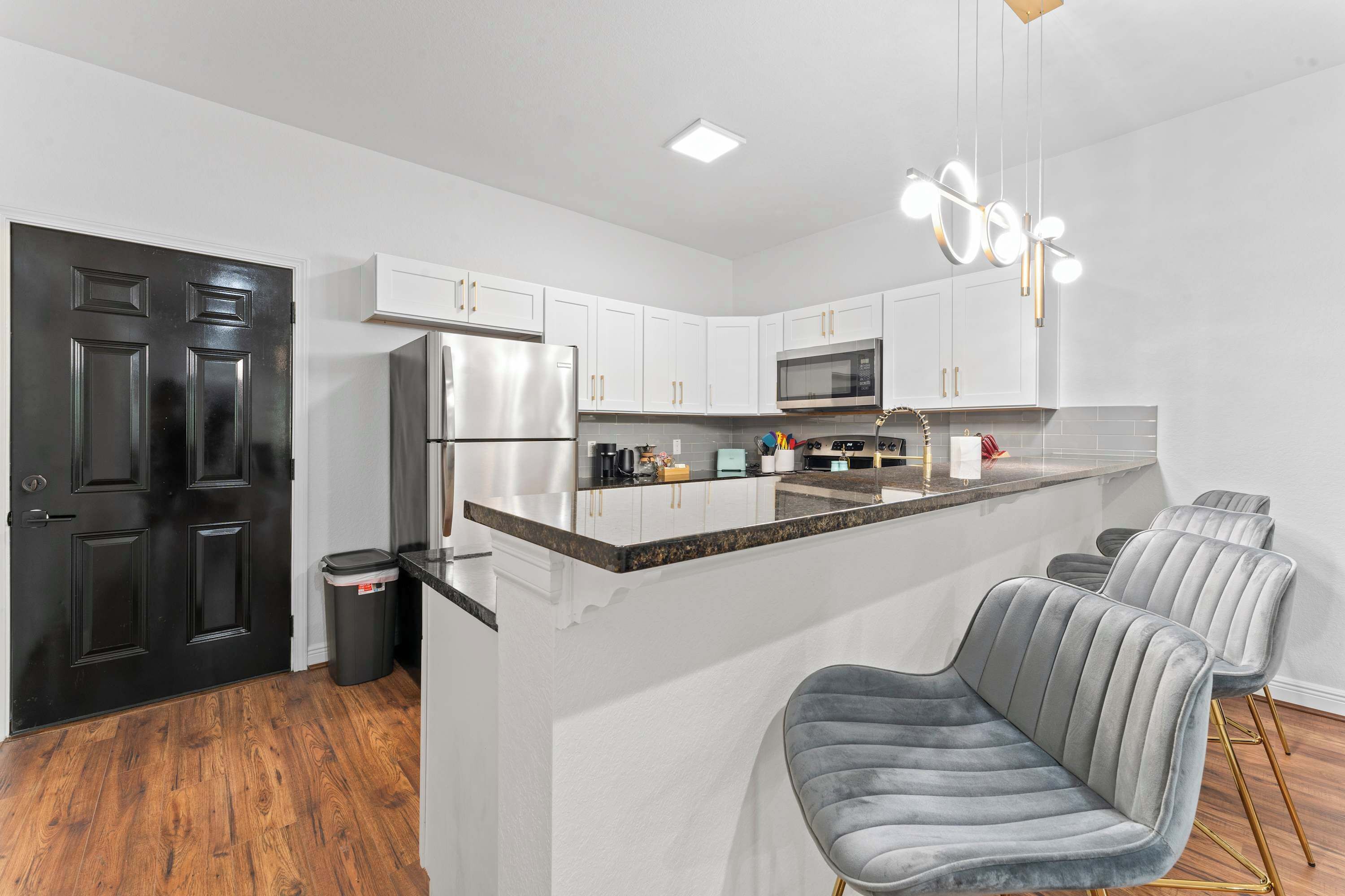 A modern kitchen with white cabinets, stainless steel appliances, and a central island with bar stools.