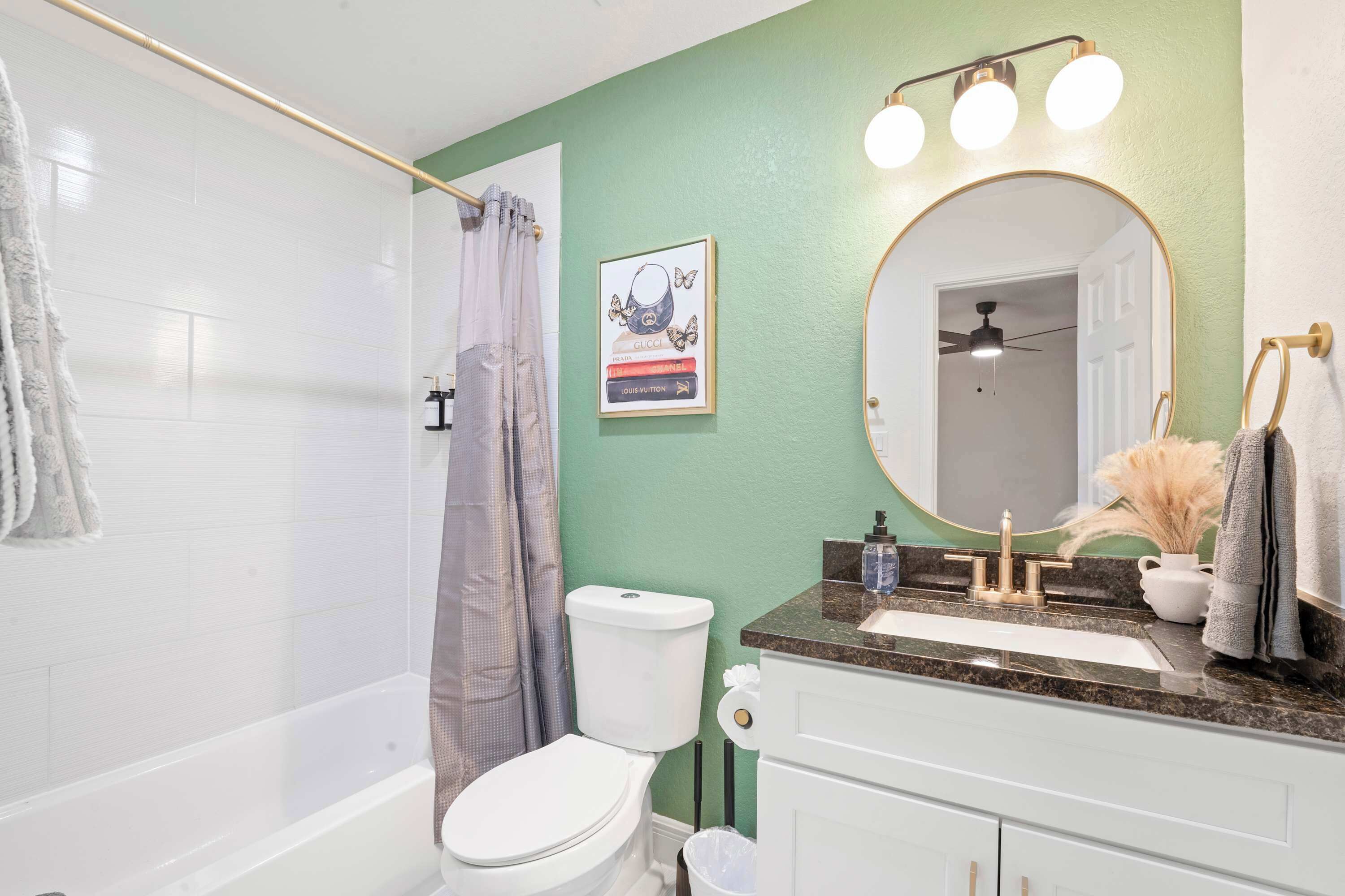 A bathroom with a bathtub, toilet, vanity, and a mirror.