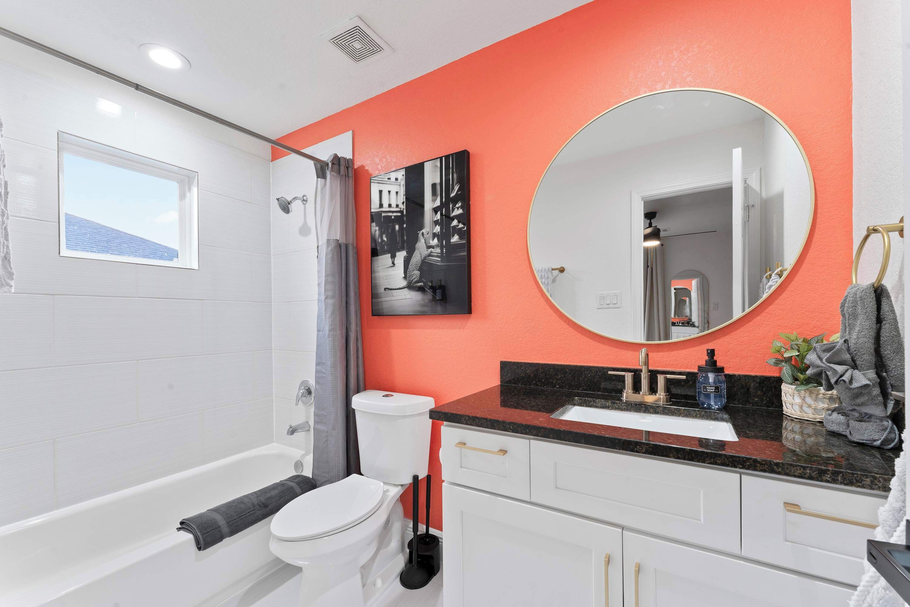 A modern bathroom with a white bathtub, a toilet, a sink, and a large mirror.