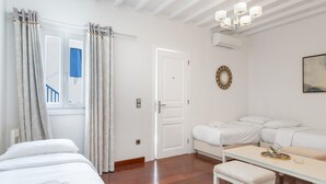 Ett hotellrum med en säng, ett bord, en bänk, en dörr och ett fönster med gardiner.