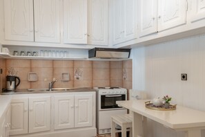 Een koelkast, een oven, een kookplaat, kookgerei, borden en bestek