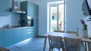 Una cuina moderna amb armaris de blau clar, forn integrat i zona de menjador amb taula i cadires.