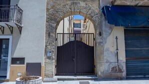 Una entrada tancada amb un arc de pedra, una reixa metàl·lica i una façana d'edifici amb una tenda blava.