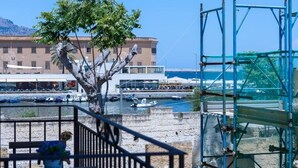 Vistes costaneres amb un arbre, un edifici i embarcacions.