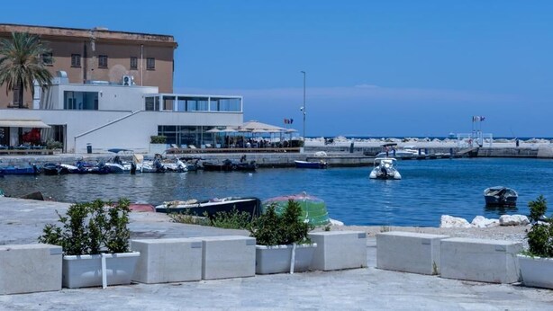 Un port esportiu amb vaixells, un edifici modern i un cel blau clar.