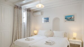 A hotel room with two beds, a nightstand with a lamp, and two framed pictures on the wall. - Apartment 'Le Coq' with Balcony, Wi-Fi and Air Conditioning (Mykonos)